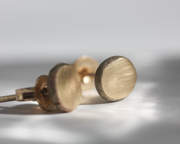 Close-up of a pair of gold earrings on a light gray background