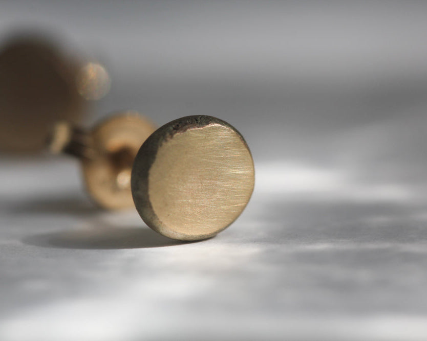 Close-up of a gold cylindrical object on a reflective surface with a blurred background
