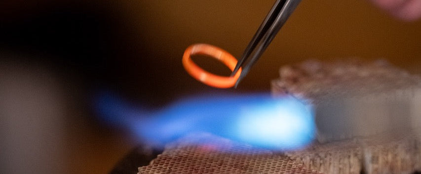 Person soldering an ethical gold wedding ring with a blue flame. 
